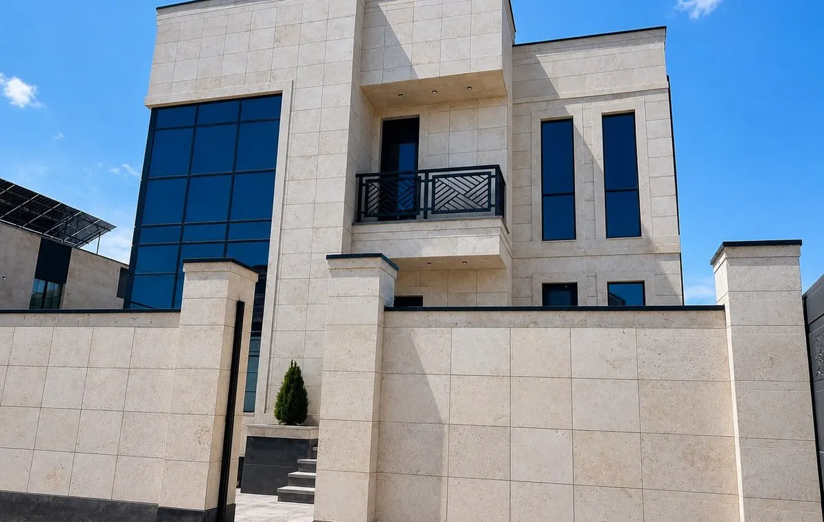 Two-storey private house with light stone cladding and blue-tinted windows